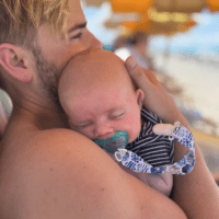 gay dad via surrogacy holding newborn baby